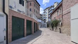 Une ruelle étroite bordée de bâtiments des deux côtés, avec des façades en briques et des portes vertes.