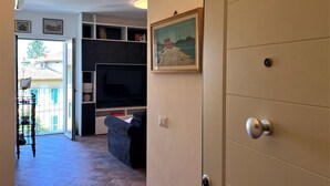 Un salon avec un canapé, une télévision et des étagères.
