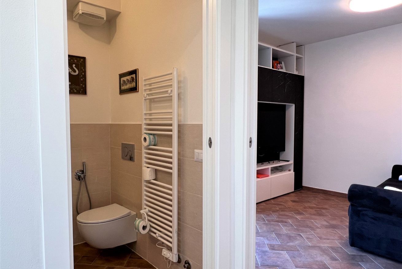 Ein kompakter Wohnraum mit Toilette, einem weißen Heizkörper, einem Fernseher und einem Sofa.