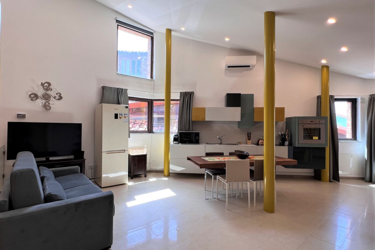 Een moderne woonkamer met een bank, een flatscreentelevisie en een eethoek met een tafel en stoelen.