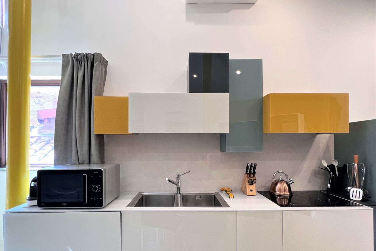 A modern kitchen with a microwave, sink, and various utensils.