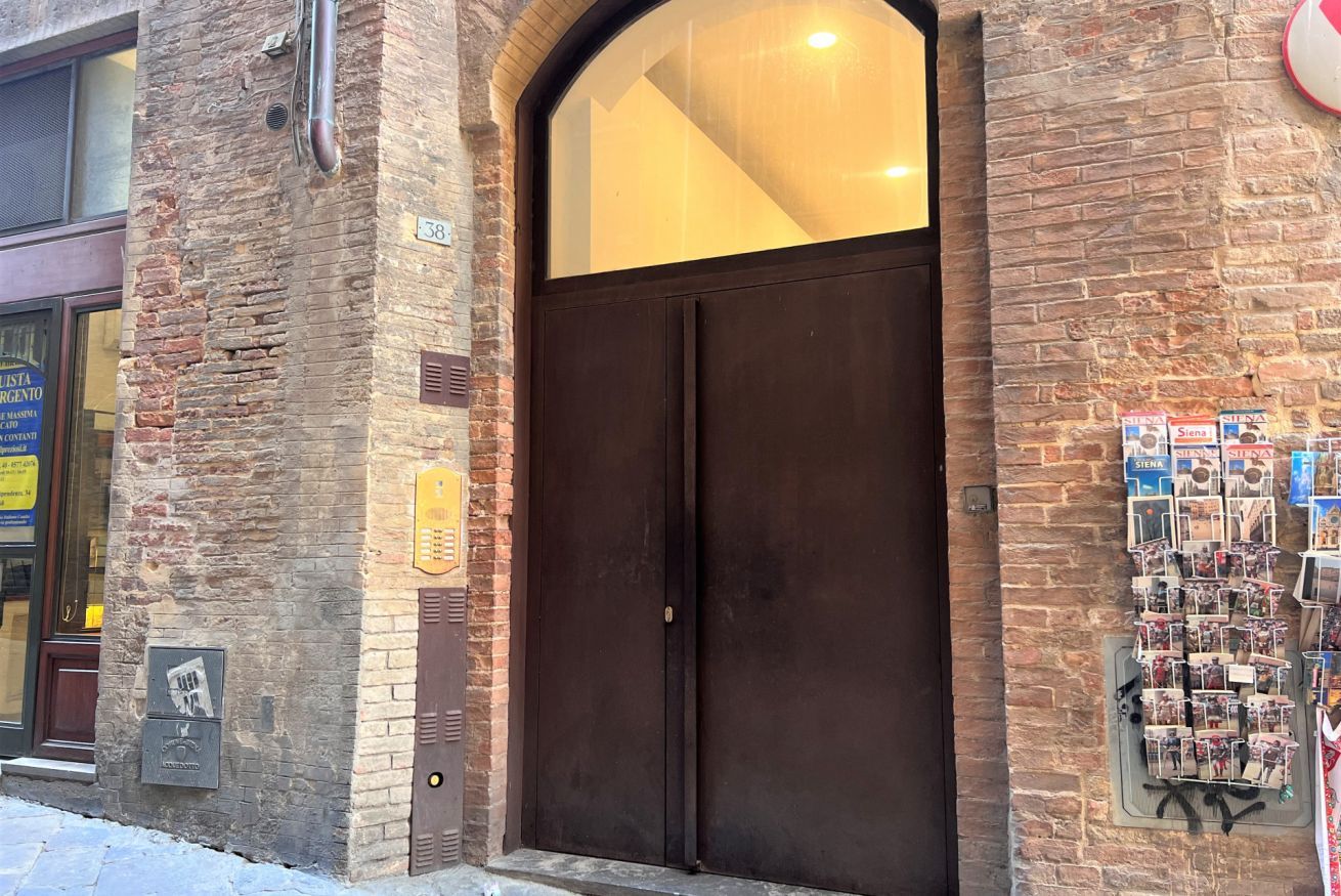A brick building with a large, dark wooden door and a small window above it.