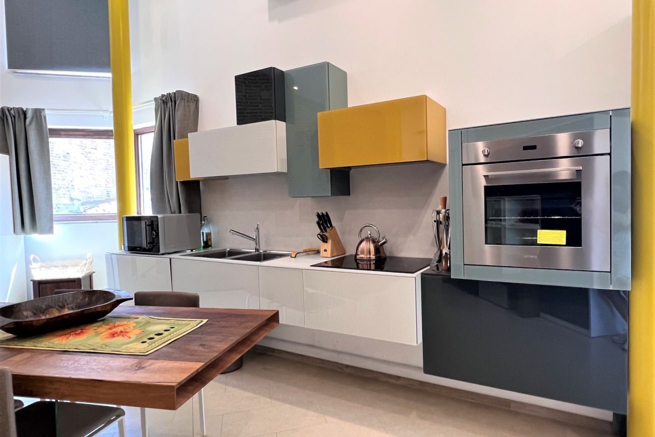 Eine moderne Küche mit weißen Schränken, einem eingebauten Backofen und einem Holztisch.