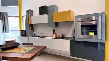 Eine moderne Küche mit weißen Schränken, einem eingebauten Backofen und einem Holztisch.