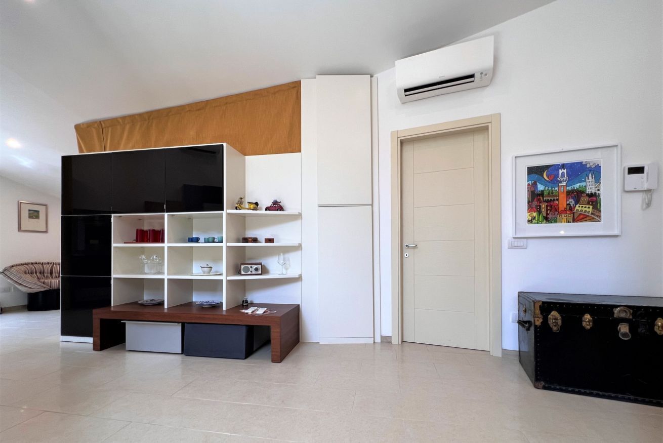 A modern living room with a black entertainment unit, white shelves, a wooden coffee table, and a door with a cityscape painting.