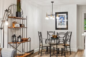 A dining area with a metal chandelier, a framed poster, and a table with chairs. - Alpine Find! 2BR Condo in Prime Location | Hot Tub + Easy Trail Access (Telluride)