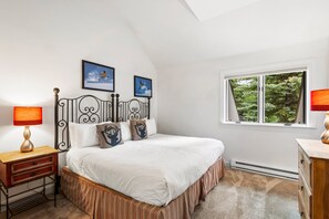 A bedroom with a bed, two bedside lamps, a window with a view of trees, and two framed pictures on the wall. - Alpine Find! 2BR Condo in Prime Location | Hot Tub + Easy Trail Access (Telluride)