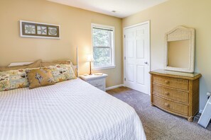 Un dormitorio con cama, mesita de noche, cómoda, ventana y puerta.