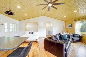 Une pièce spacieuse comprenant un lit, un canapé en cuir, une table à manger et un ventilateur de plafond.