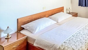 A neatly made bed with white linens, a wooden headboard, and a nightstand with a lamp. - Stunning apartment in Nova Vas (Nova Vas)