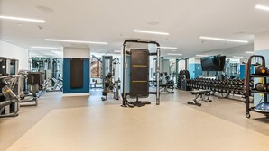 A modern gym with various exercise equipment, including weight machines, free weights, and cardio machines.