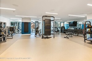 Ein modernes Fitnessstudio mit verschiedenen Trainingsgeräten, darunter Kraftgeräte, Kurzhanteln und Cardiogeräte.