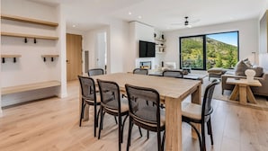 A modern interior with a dining area, seating, and a large window offering a view.