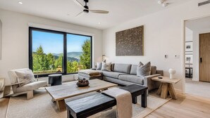 A modern living room with a large window, a sofa, a coffee table, and a ceiling fan.