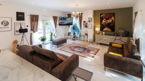 Un salon spacieux avec un grand canapé, une table basse et un coin repas offrant une vue sur la Tour Eiffel.