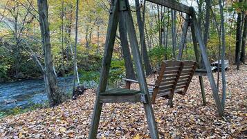 A wooden swing set in a forested area with a river in the background.