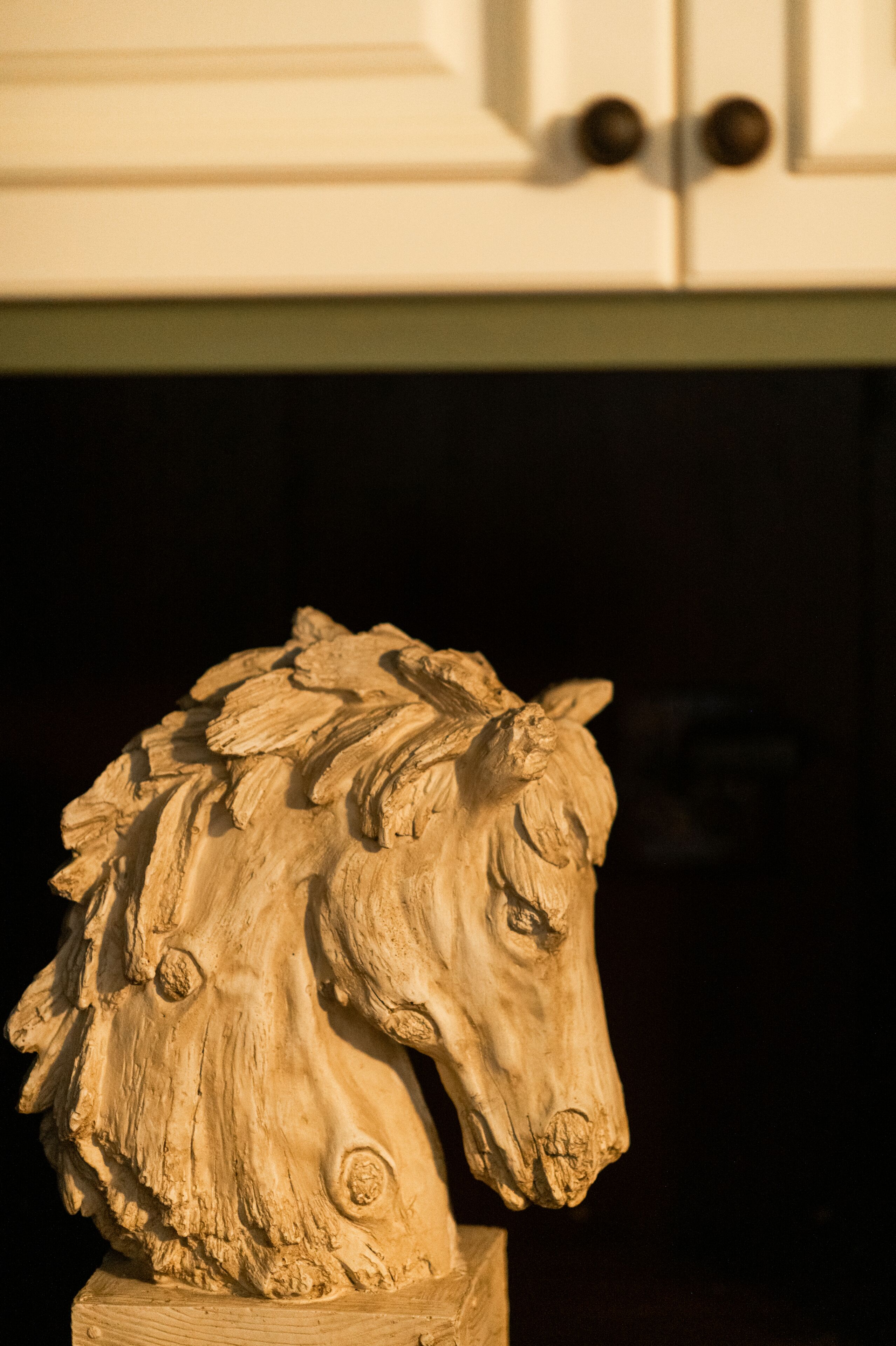 A sculpture of a horse's head mounted on a pedestal.