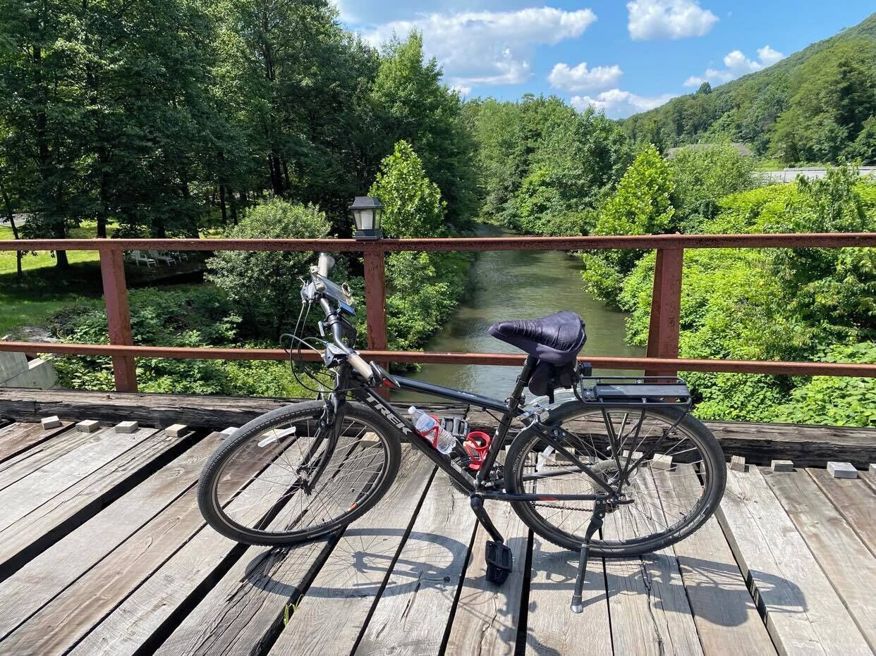 A bicycle on a wooden deck with a view of a river and greenery in the background.