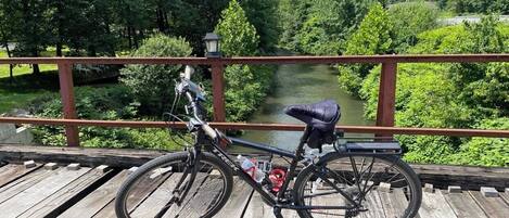 A bicycle on a wooden deck with a view of a river and greenery in the background.