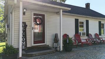 A house with a 'WELCOME' sign, a front door, and a porch with Adirondack chairs.