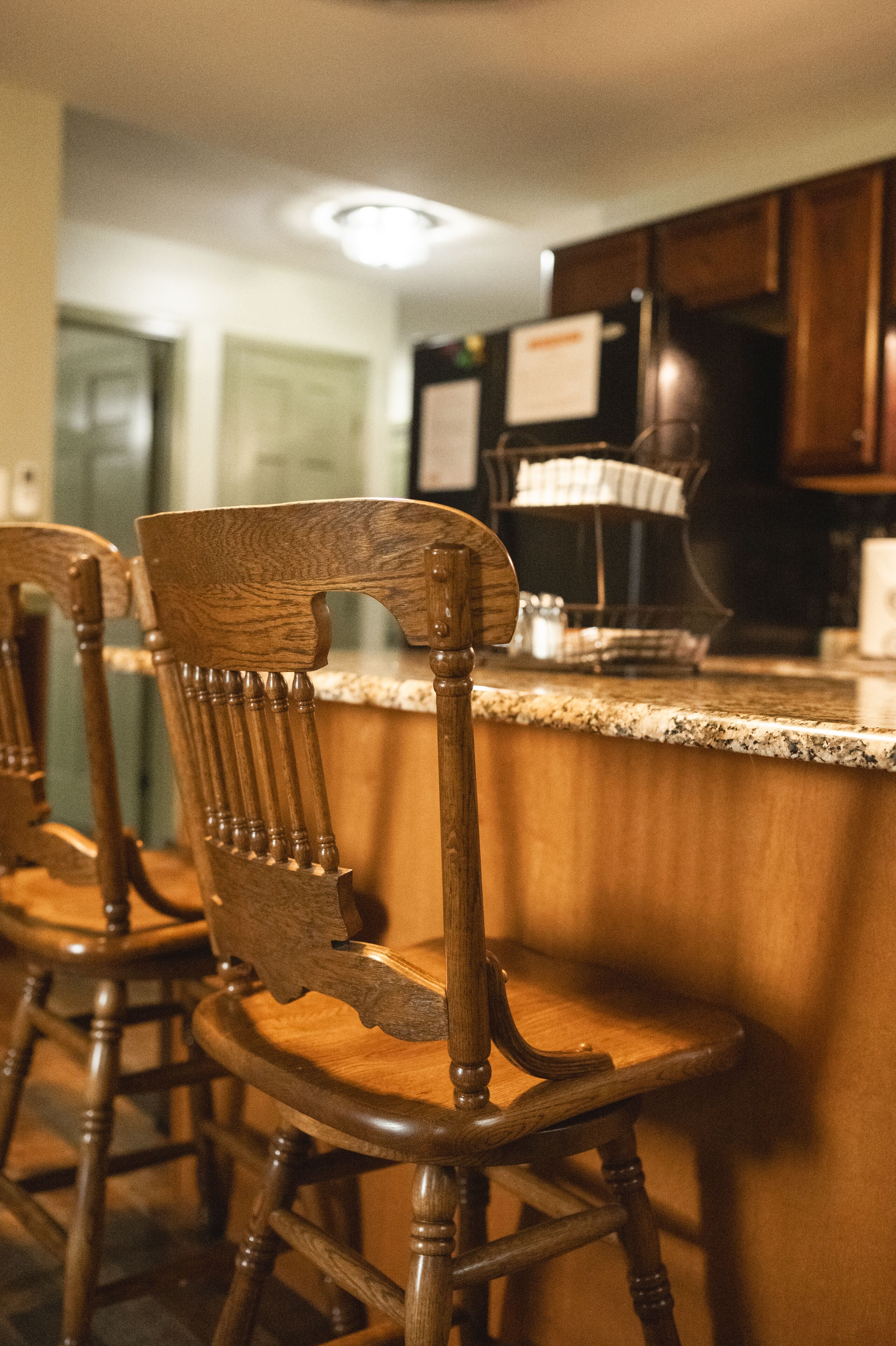 A kitchen area with wooden chairs and a granite countertop.