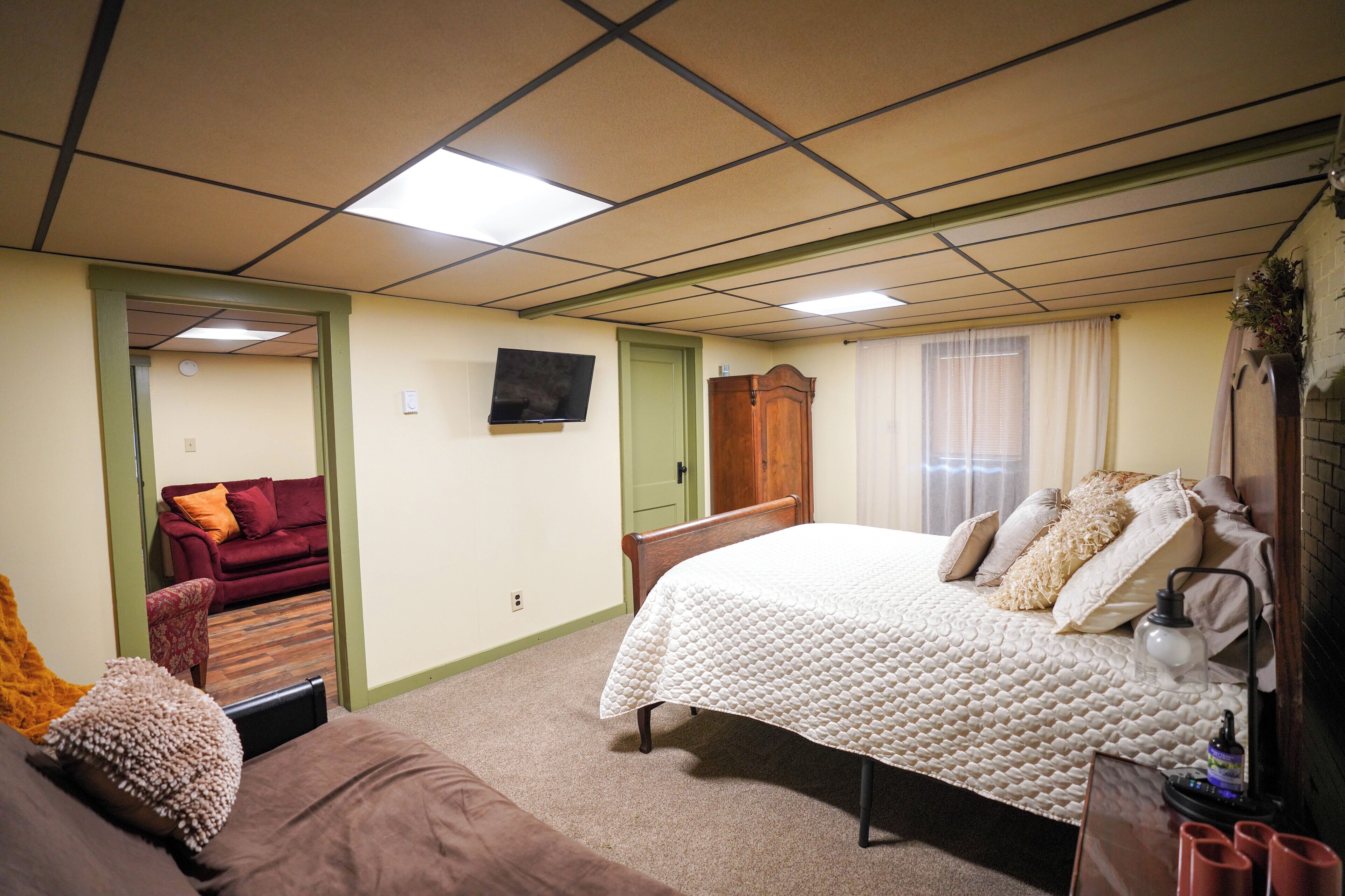 Un dormitorio con una cama grande, cabecera de madera, mesita de noche y televisión en la pared.