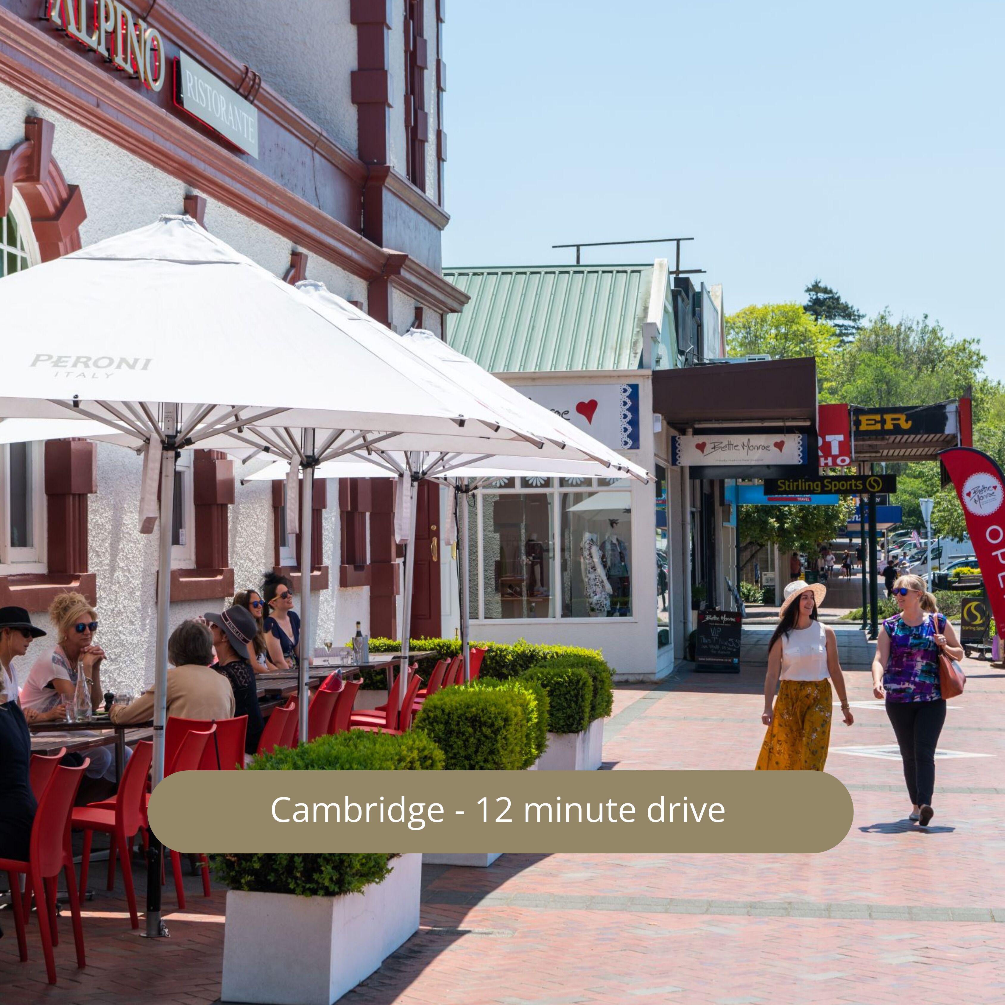 An outdoor dining area with red chairs and white umbrellas, a storefront with a sign reading "Stirling Sports," and a clear sky.
