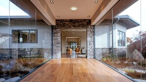 Ein modernes Haus mit einer Steinaußenwand, einem Glaseingang und einem Holzboden, der in einen Wohnbereich führt.