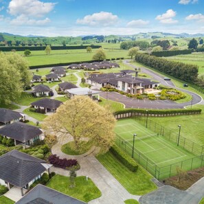 A residential area with houses, a tennis court, and a road. - Karapiro Villas Resort (Karapiro)