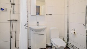 Baño con ducha, lavamanos, inodoro y espejo.