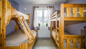 Un dormitorio con literas, un radiador, una ventana con cortinas y una planta en maceta.