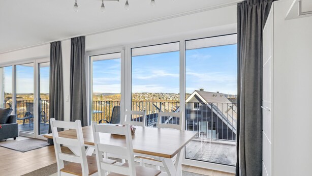 Een moderne kamer met een groot raam, een eettafel en stoelen.