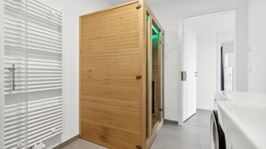 Een gang met een houten schuifdeur, een witte radiator en een wasmachine.