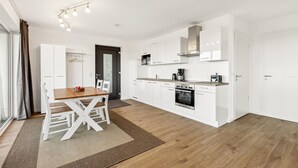 Een moderne keuken met witte kasten, een houten eettafel en een inbouwoven.