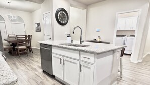 Une cuisine moderne avec des meubles blancs, un plan de travail en granit et un lave-vaisselle.
