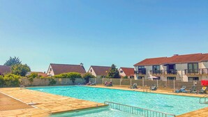 A swimming pool with a tiled deck, surrounded by houses with red-tiled roofs. - Nice home in Bredene with heated swimming pool (Bredene)
