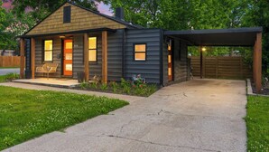 Une maison à deux étages avec un porche abrité et un petit jardin.
