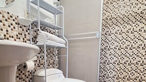 Un baño con inodoro, lavabo, ducha y suelo de baldosas.