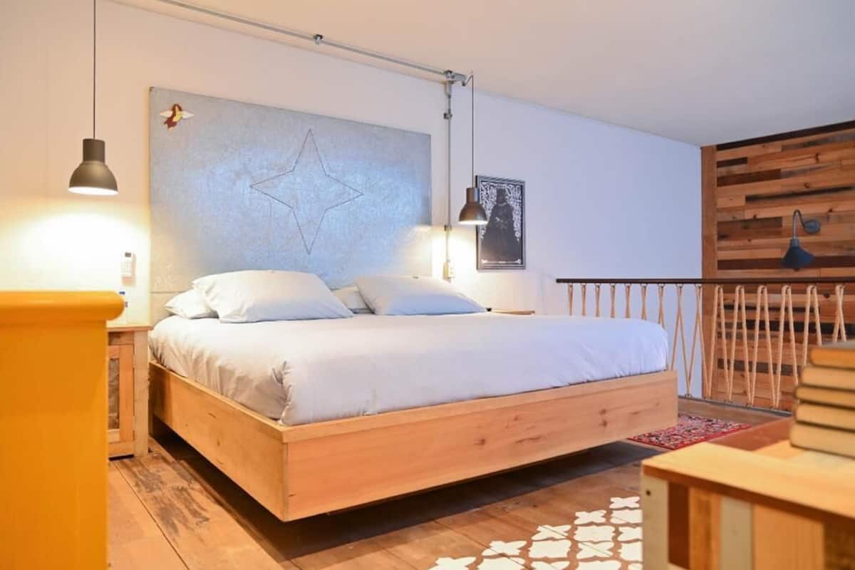 A modern bedroom with a wooden bed, a star-shaped wall decoration, and a wooden headboard.