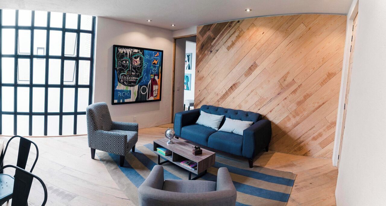 A modern living room with a blue sofa, patterned armchair, and a coffee table.
