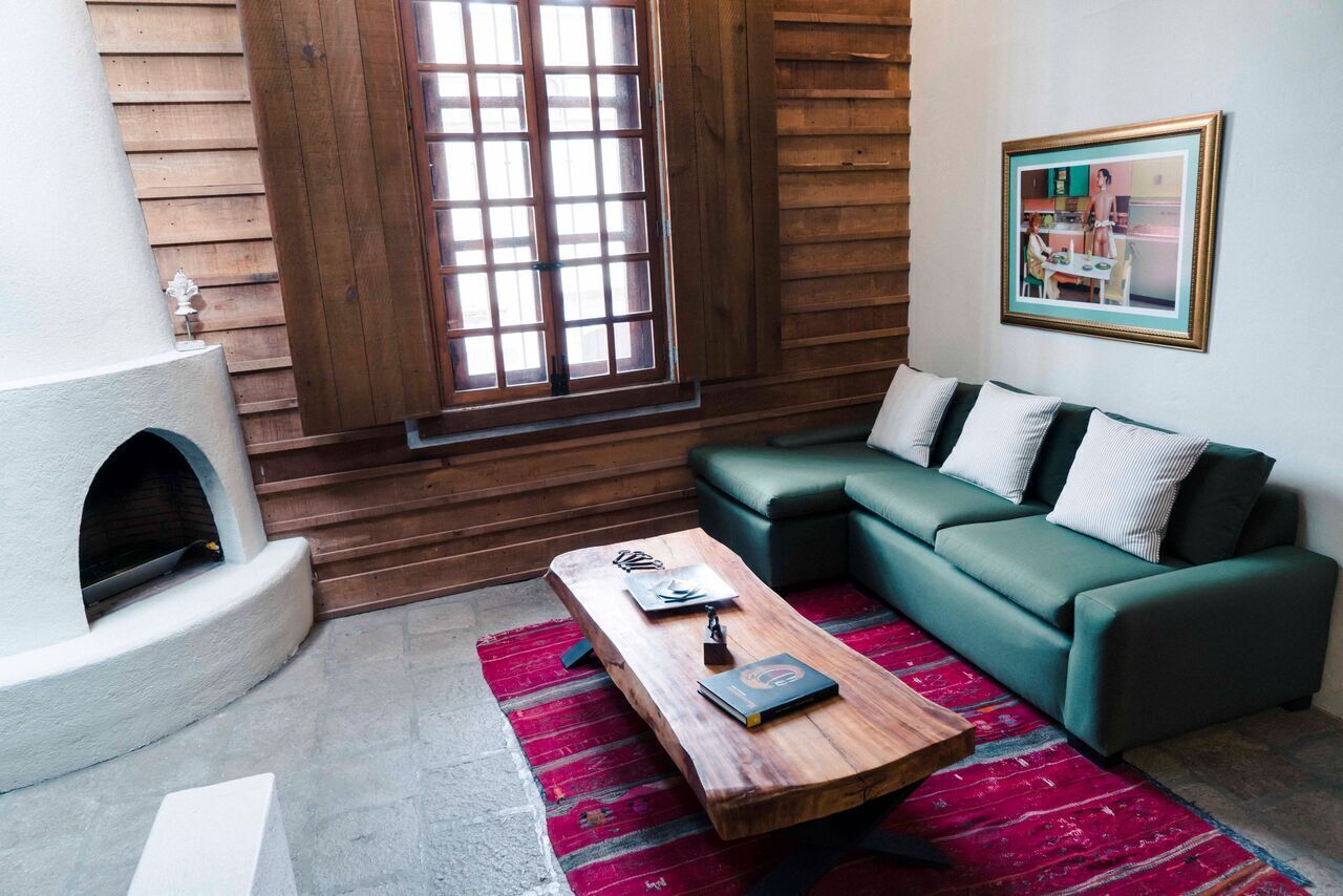 Una sala de estar acogedora con chimenea, un sofá verde, una mesa de centro de madera y un tapete rojo.