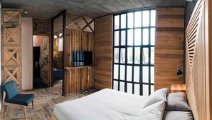 Un dormitorio con una cama grande, una silla, un televisor y una ventana.