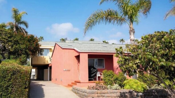 Un edificio residenziale con facciata rossa, un ingresso principale e un vialetto lastricato.