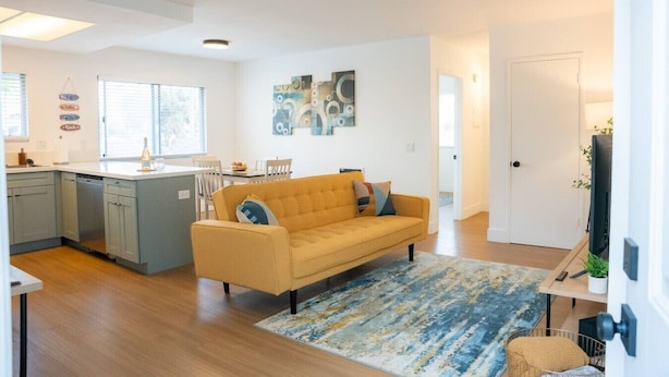 A modern living room with a sofa, a dining area, and a kitchen.