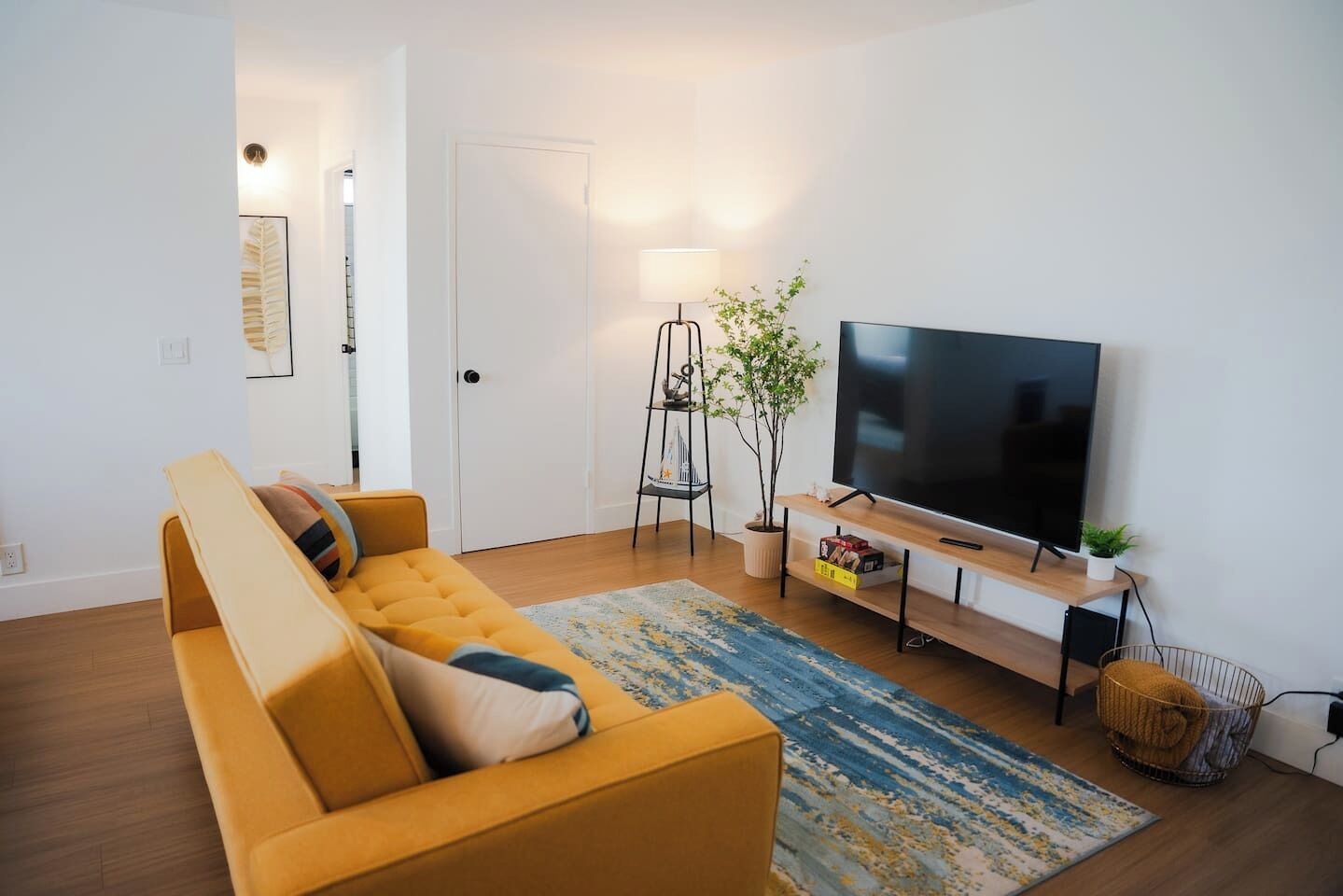 Ein modernes Wohnzimmer mit einer Couch, einem Fernseher, einer Lampe und einer Pflanze.