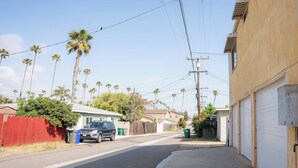 A residential street with houses, a parked car, and a sidewalk.