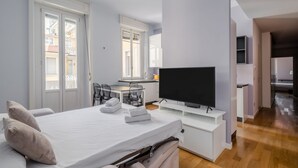 Ein modernes Hotelzimmer mit Bett, Schreibtisch, Fernseher und Blick auf die Stadt.