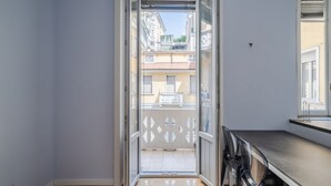 Ein schmaler Flur mit einer Glastür, die auf einen Balkon im Freien führt.