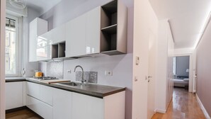 Eine moderne Küche mit weißen Schränken, einer schwarzen Arbeitsplatte und einem Gasherd.