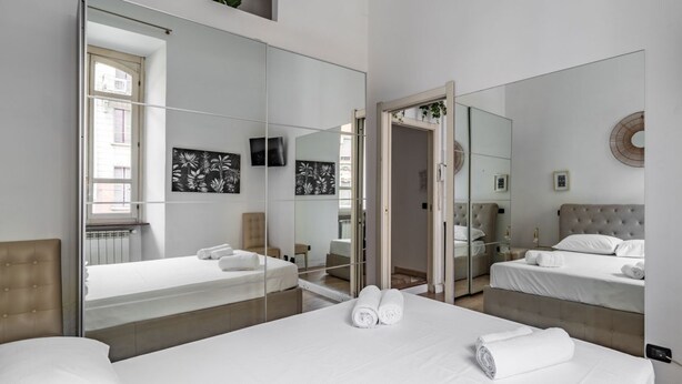 Une chambre avec deux lits, un grand miroir et des œuvres d’art accrochées aux murs.